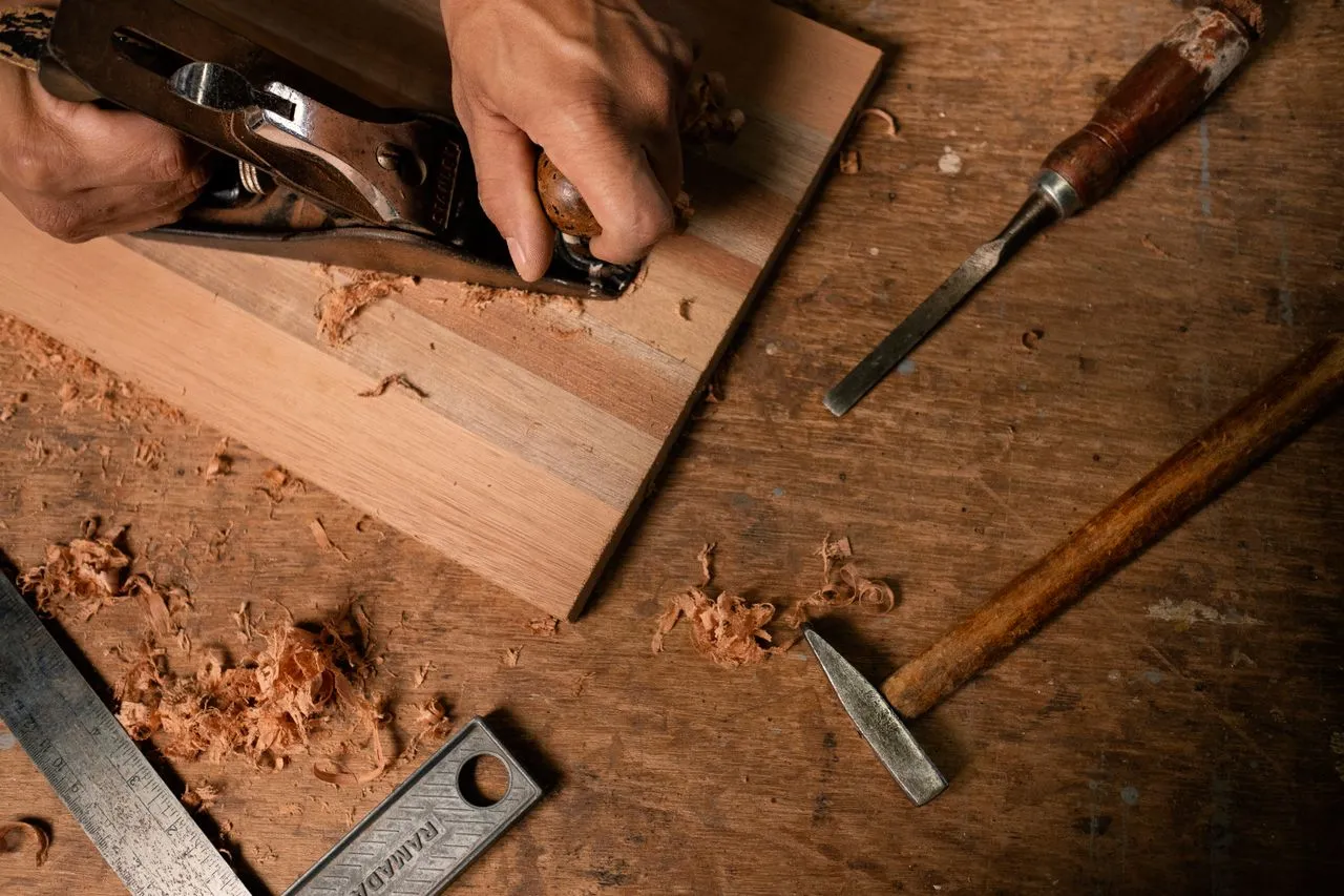 Close-up of a hand plane, chisels, and wood shavings on a workbench, representing skilled handyman and joinery work